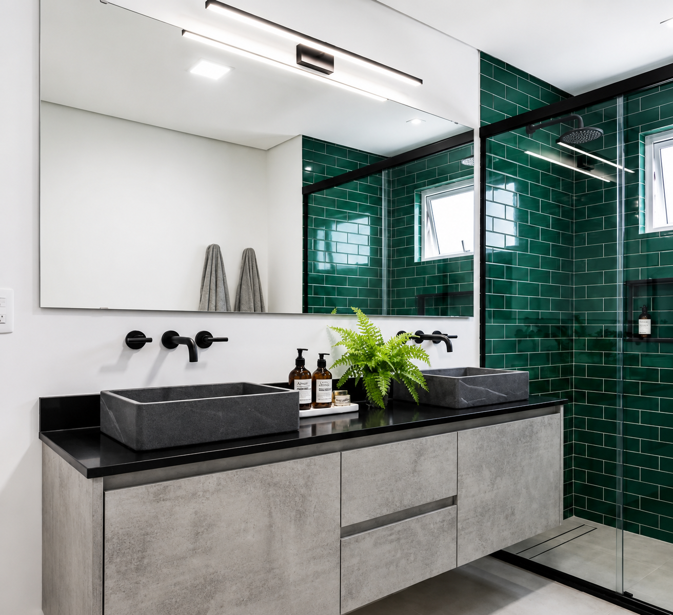 Banheiro contemporâneo com marcenaria cimento queimado, bancada em granito preto, cubas em pedra e revestimento verde esmeralda