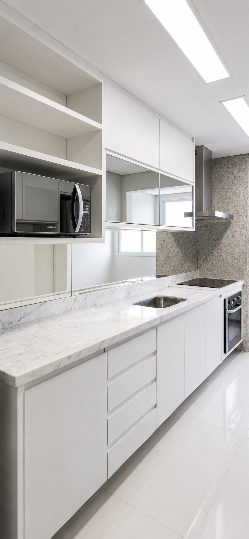 Cozinha planejada em laca branca com bancada em mármore Carrara, espelho bronze e iluminação embutida